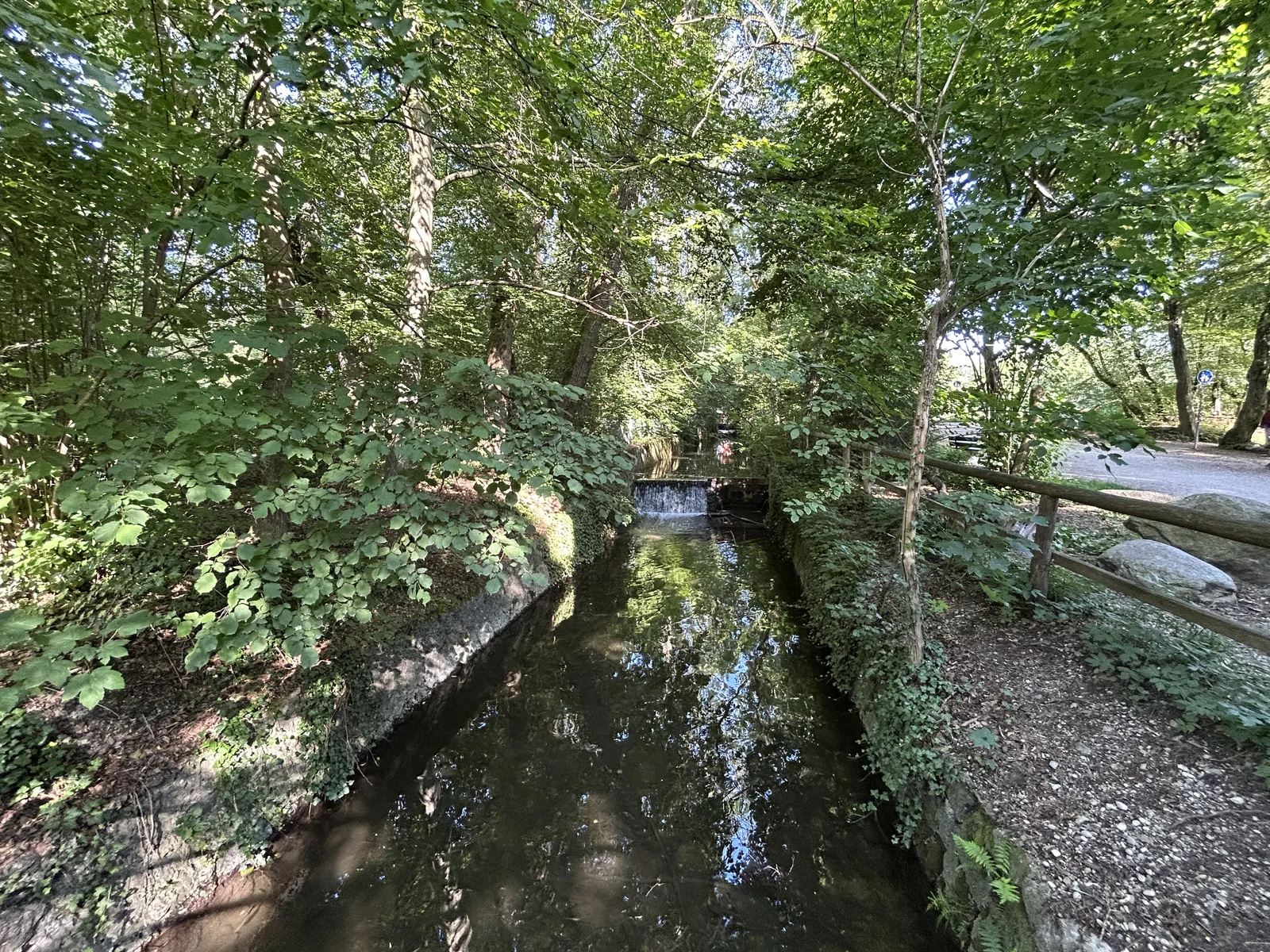 Blick von der Brücke auf den kleinen Wasserfall im Pasinger Stadtpark